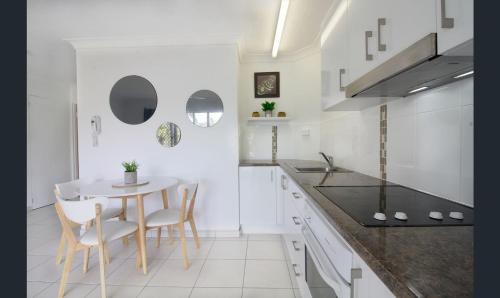 a white kitchen with a table and chairs at Bay of Palms in Gold Coast