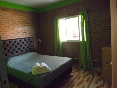 1 dormitorio con 1 cama con cortinas verdes y ventana en Cabañas San Jose in 