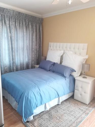 a bedroom with a bed with blue sheets and pillows at Lalela House in Johannesburg