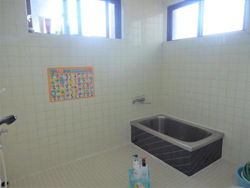 a bathroom with a tub in a white tiled wall at Minshuku Kuroshima in Kuroshima