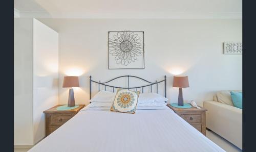 a bedroom with a white bed with two lamps at Bay of Palms in Gold Coast