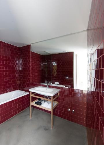 a red tiled bathroom with a sink and a tub at Melgaço Alvarinho Houses in Melgaço