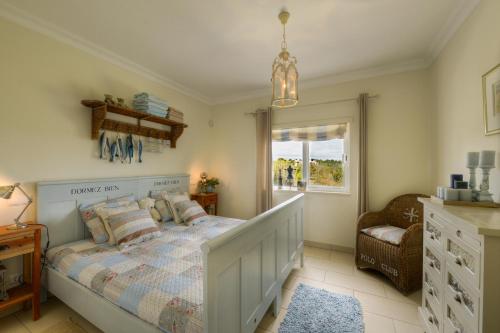 een slaapkamer met een bed, een stoel en een raam bij Casa Marinha Beach in Lagoa