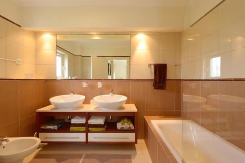 een badkamer met 2 wastafels, een bad en een spiegel bij Casa Marinha Beach in Lagoa