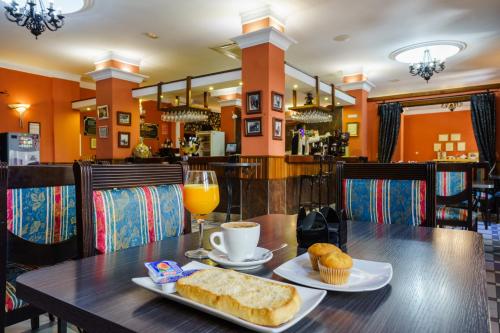 a table with a plate of bread and a glass of orange juice at Hotel España in Lanjarón