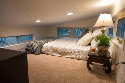 a bedroom with a bed and a table with a lamp at Montana Escape Elegant Tiny House in Waco Near Magnolia in Waco