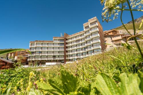 un grand bâtiment au sommet d'une colline avec de l'herbe dans l'établissement Résidence Pierre & Vacances Le Gypaète, à Val Thorens