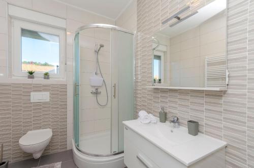 a bathroom with a shower and a toilet and a sink at Apartments Luxury and Sea View in Brodarica