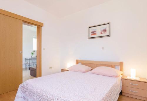 ein Schlafzimmer mit einem weißen Bett mit zwei rosa Kissen in der Unterkunft Apartments Ljuba - in center & close to the beach in Duba