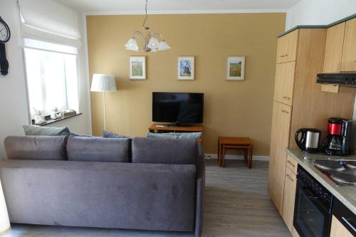 Una sala de estar con un sofá y un televisor. en Ferienwohnung Maigloeckchen 17, en Ostseebad Karlshagen