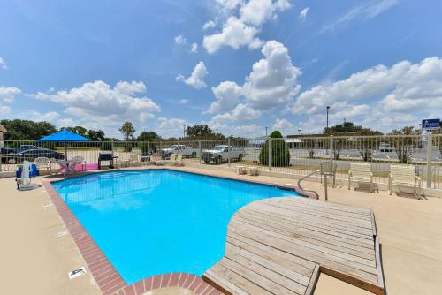 a large swimming pool with a wooden deck next to a parking lot at Quality Inn in Gonzales