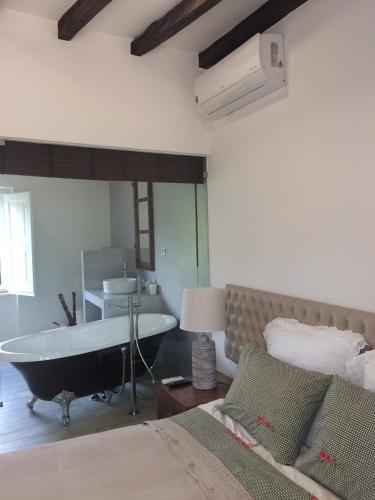 a bedroom with a tub and a bed and a sink at Quinta Ribeira do Labrador - Lisbon West Wine Route in Alenquer