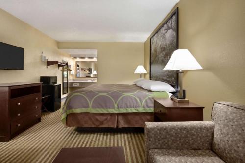 a hotel room with a bed and a chair at Super 8 by Wyndham Ruston in Ruston