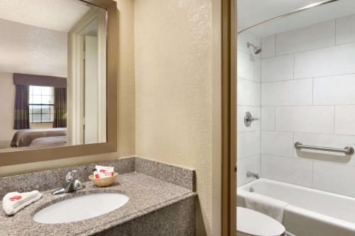 a bathroom with a sink and a tub and a mirror at Super 8 by Wyndham Ruston in Ruston