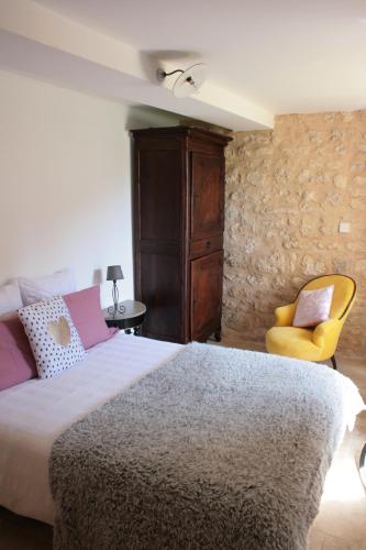 a bedroom with a bed and a yellow chair at AU NID DES VIGNES in Cahuzac-sur-Vère