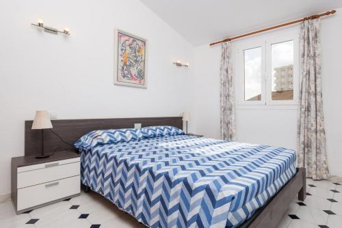 Un dormitorio con una cama azul y blanca y una ventana. en Es Mallorqui, en Puerto de Alcudia