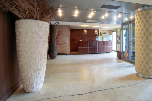 a lobby with two large vases on the floor at Hotel Aleramo in Asti