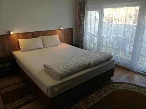 a bed in a bedroom with a large window at Family Hotel "May" in Petrich
