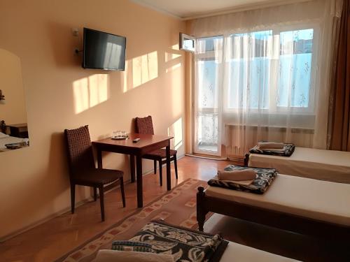 a small room with a table and a bed and a window at Family Hotel "May" in Petrich