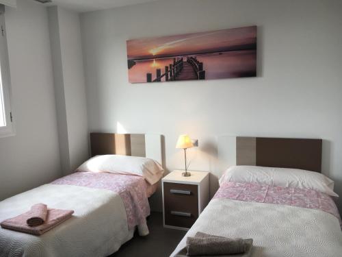 a bedroom with two beds and a picture on the wall at Apartamento Aqua Nature Delfin in La Mata