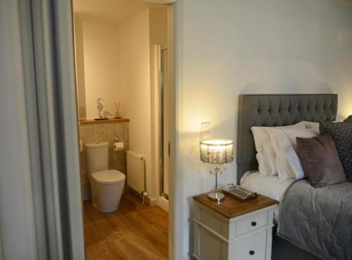 a bedroom with a bed and a bathroom with a toilet at Faskally Shores in Pitlochry