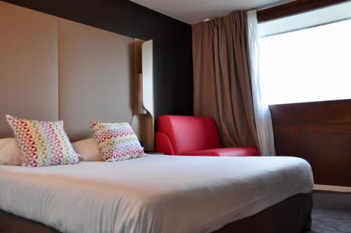 a hotel room with a bed and a red chair at Campanile SETE - Balaruc in Balaruc-le-Vieux
