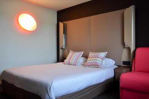 a bedroom with a bed and a red chair at Campanile SETE - Balaruc in Balaruc-le-Vieux