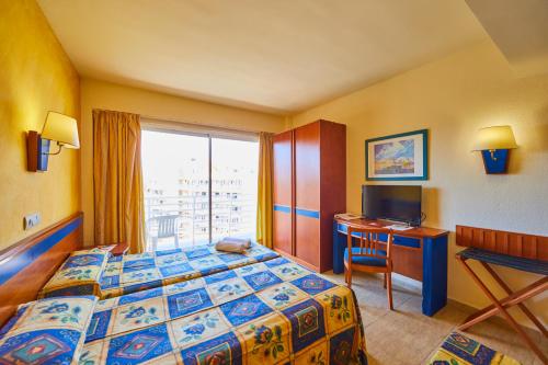 a hotel room with a bed and a desk and a window at MLL Palma Bay Club Resort in El Arenal