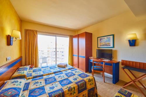 Cette chambre comprend un lit, un bureau et une fenêtre. dans l'établissement MLL Palma Bay Club Resort, à El Arenal
