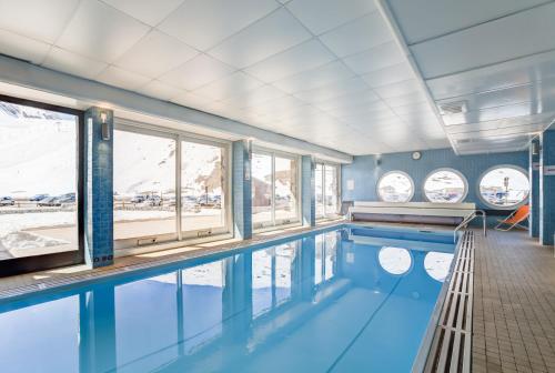 a swimming pool with blue water and windows at Résidence Pierre & Vacances Inter-Résidences in Tignes