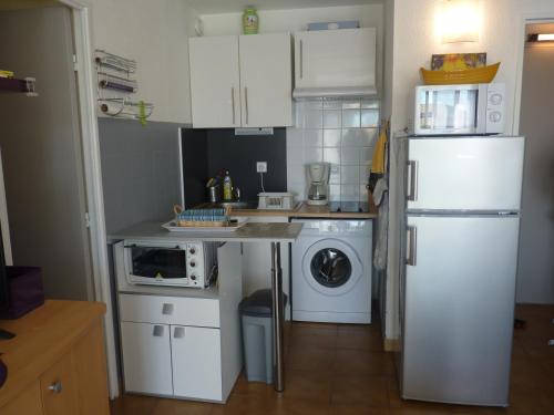Il comprend une cuisine équipée d'un réfrigérateur blanc et d'un lave-linge. dans l'établissement Appartement T2 Cabine, Les Balcons de la Méditerranée, Narbonne Plage, à Narbonne-Plage