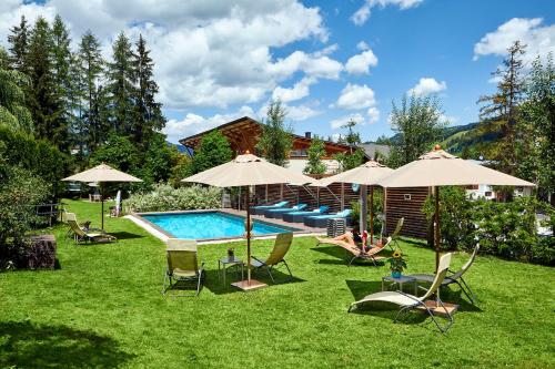 a pool with chairs and umbrellas in a yard at Dolomit Boutique Hotel in La Villa