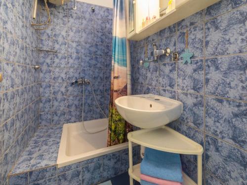 La salle de bains est pourvue de carrelage bleu, d'un lavabo et d'une douche. dans l'établissement Apartment IVA MAN, à Crikvenica