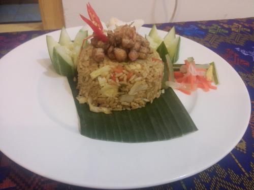 Un plato de comida con arroz y frijoles en una hoja de plátano. en Intan Inn Hostel, en Gili Trawangan