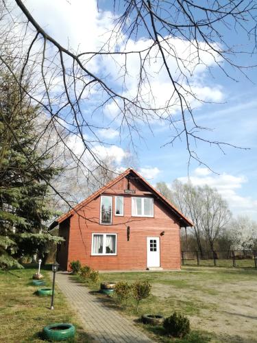 a red house in a field with a tree at Center Angelos in Bronków
