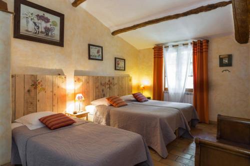 a bedroom with two beds and a window at Le Degoutaud in Le Barroux