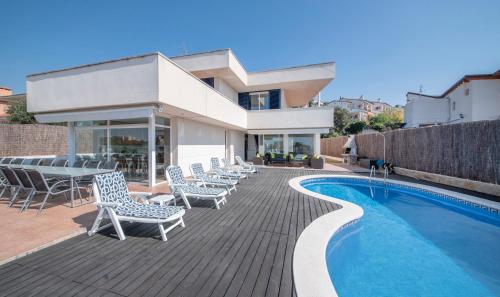 a deck with chairs and a swimming pool next to a house at Villa Med in Sitges