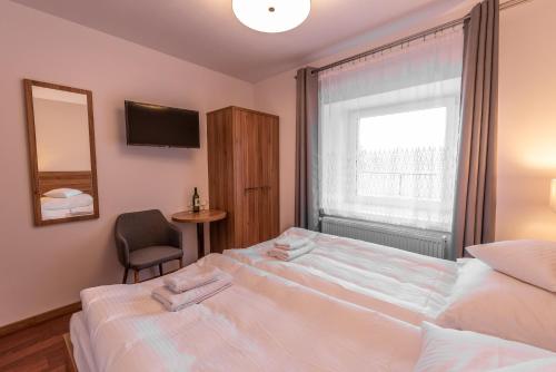 a bedroom with two beds and a window and a chair at Apartamenty ZYGFRYD 28C 2 in Bystrzyca Kłodzka