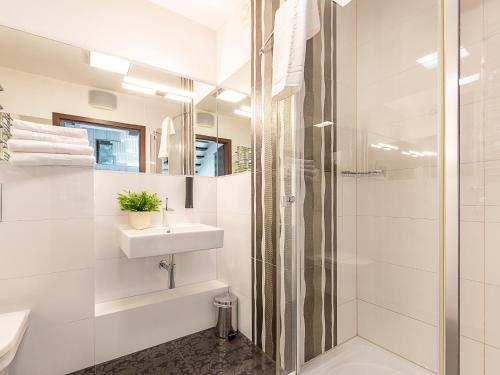 baño blanco con ducha y lavamanos en VacationClub - Sand Hotel Apartament 409, en Kołobrzeg