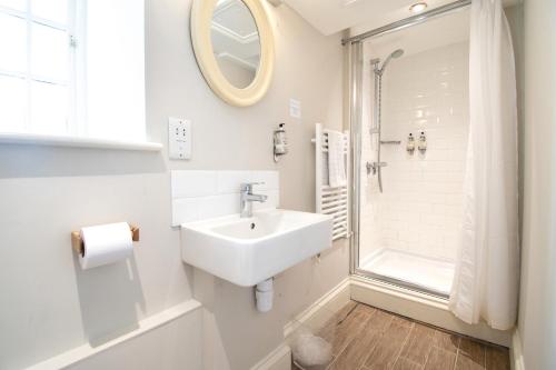 a white bathroom with a sink and a shower at The Farmhouse at Bodnant Welsh Food in Conwy