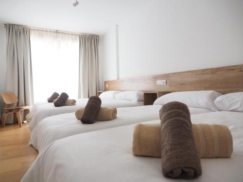 a hotel room with three beds with towels on them at PENSION ROSELLA in O Pedrouzo