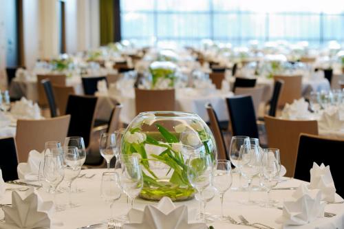 a dining room with tables with glasses and flowers at Atlantic Congress Hotel Essen in Essen