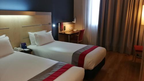 pokój hotelowy z 2 łóżkami i stołem w obiekcie Holiday Inn Express Málaga Airport, an IHG Hotel w Maladze