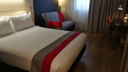 Habitación de hotel con cama y silla en Holiday Inn Express Málaga Airport, an IHG Hotel en Málaga