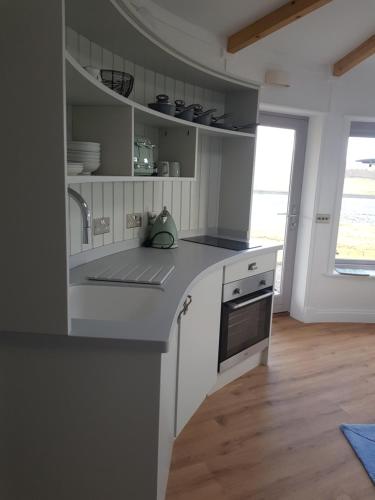 Skeabost的住宿－Skye Cabins，白色的厨房设有水槽和炉灶。