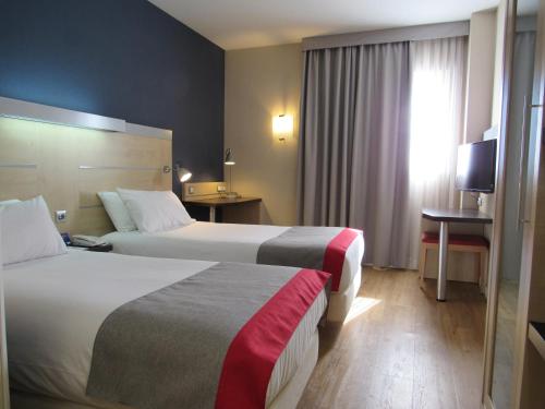 een hotelkamer met 2 bedden en een televisie bij Holiday Inn Express Málaga Airport, an IHG Hotel in Málaga
