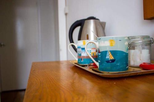 two coffee cups sitting on a tray on a table at Drang house all rooms have stairs in Padstow