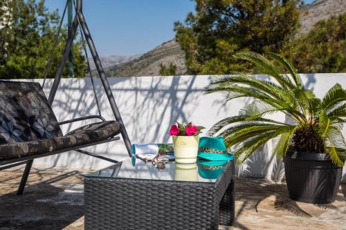 a patio table with a chair and a plant at Apartments Nada in Dubrovnik