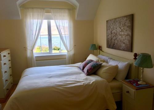 a bedroom with a large white bed with a window at Foxglove House in Valentia Island