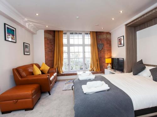 a bedroom with a bed and a couch and a television at Cocoa Suites Luxury Apartments in York